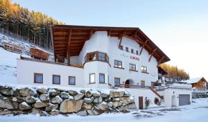a large white building with a wooden roof in the snow at Apart Lukas in Ischgl
