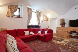 a red couch in a living room with a tv at Appartamenti Royal in San Vito di Cadore