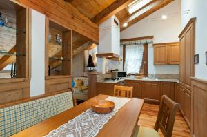 a kitchen with wooden cabinets and a wooden dining table at Appartamenti Royal in San Vito di Cadore