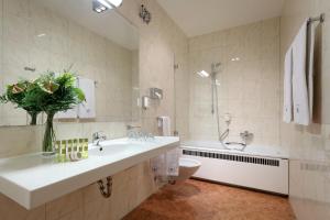 
a bathroom with a tub, sink and mirror at Eurostars Park Hotel Maximilian in Regensburg
