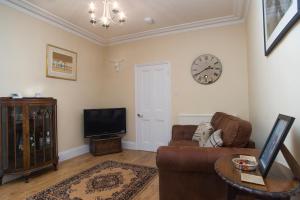 salon z kanapą i zegarem na ścianie w obiekcie The Lodge at Heathfield w mieście Ledbury