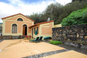 une maison avec un mur en pierre et 2 chaises sur une terrasse dans l'établissement Gordejuela 2, à Los Realejos