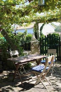 una mesa de picnic de madera y dos sillas bajo un árbol en Casa Rural Vella da Rivera en O Sisto