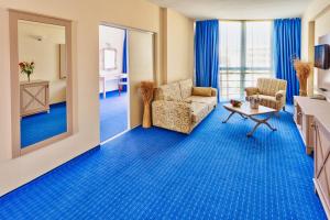 サニービーチにあるDAS Club Hotel Sunny Beach - All Inclusiveの鏡、ソファ、椅子が備わる客室です。