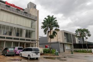 a parking lot with cars parked in front of a building at RedDoorz Plus @ Kapuk Business Park in Jakarta