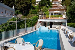 a white swimming pool with a white couch and chairs at Hotel Villa Brunella in Capri
