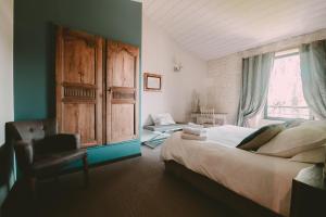 a bedroom with a bed and a chair and a window at Un Banc au Soleil in Marsilly