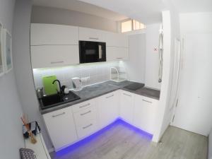 ベナルマデナにあるCasa de Locosの白いキャビネットと床の青い照明付きのキッチンが備わります。