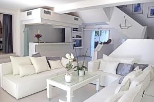 a white living room with white couches and a table at Aegialis Hotel & Spa in Aegiali