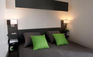 Habitación con 2 almohadas verdes en una cama en Residence U Veniqui, en Favone