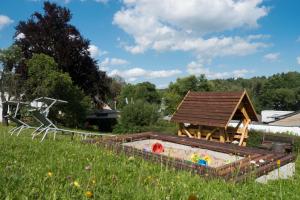 a sandbox in a field next to a playground with a house at Ferienwohnung Rennsteigblick in Tambach-Dietharz