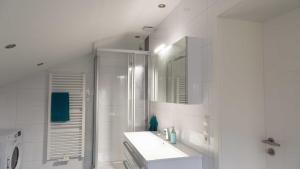 a white bathroom with a sink and a shower at Ferienwohnung Rennsteigblick in Tambach-Dietharz