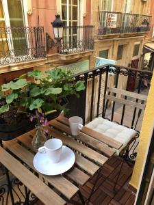 een houten tafel met twee kopjes en een stoel op een balkon bij Apartment Muñoz 1 in Alicante