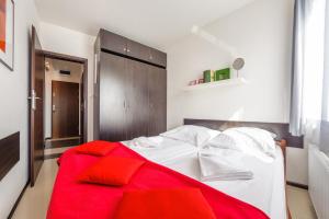 a bedroom with a white bed with a red blanket at Apartamenty Sun & Snow Lisi Jar in Jastrzębia Góra