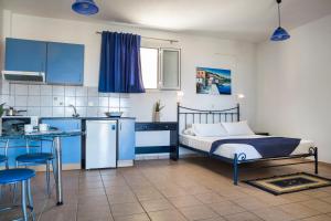 Maria's Garden Apartments في لاسي: غرفة نوم مع سرير ومطبخ مع دواليب زرقاء