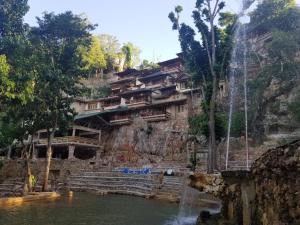 a building on the side of a mountain with a waterfall at Paraiso Caño Hondo in Los Guineos Perdidos