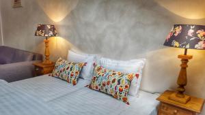 ein Schlafzimmer mit einem Bett mit Kissen und zwei Lampen in der Unterkunft Windmill Studios by Rembrandt Hotel in Bukarest