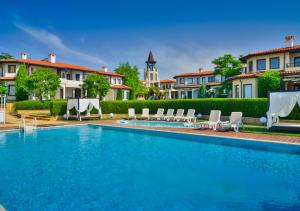 a swimming pool with chairs and a building at BlackSeaRama Golf & Villas in Balchik