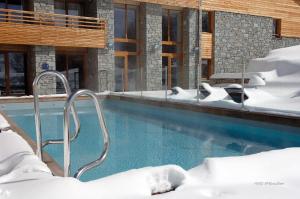 a swimming pool covered in snow next to a building at Lagrange Vacances l'Alpenrose in L'Alpe-d'Huez