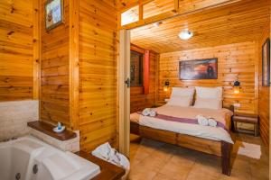 a bedroom in a log cabin with a bed and a tub at Mazal shell Zimmer in Amirim