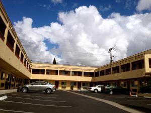 dois carros estacionados num parque de estacionamento em frente a um edifício em Harvey's Motel SDSU La Mesa San Diego em San Diego