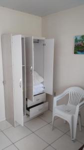 1 dormitorio con armario blanco y silla blanca en Recanto Fernandes, en Pinheira