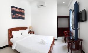 1 dormitorio con 1 cama blanca y TV en Thao Hieu Homestay Hoi An, en Hoi An