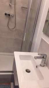een witte badkamer met een wastafel en een douche bij chambre noisy in Noisy-le-Sec