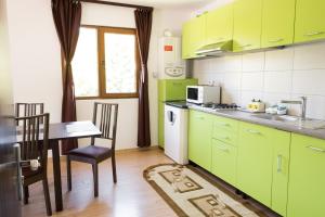 a kitchen with green cabinets and a table with chairs at Vila Alma Azuga in Azuga