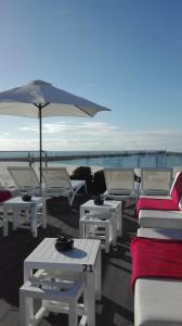 un groupe de tables et de chaises avec un parapluie dans l'établissement House Barra Beach, à Praia da Barra