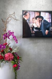 una foto colgada en una pared con un jarrón de flores en TIBUR STAR Guest House, en Settecamini