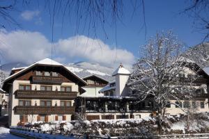 a building in the snow with mountains in the background at River Hotel Post in Chienes