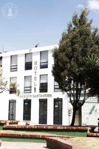 un edificio blanco con un árbol delante en Hotel Parque Santander Tunja en Tunja