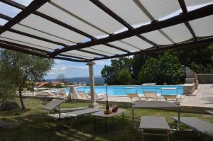 a pergola over a pool with chairs and a table at Villa Le Querciolaie in Monteverdi Marittimo