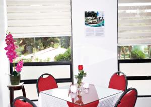 a dining room with red chairs and a white table with flowers at Hotel Parque Santander Tunja in Tunja