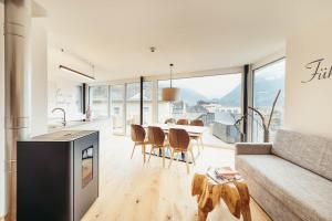 adler alpen apartments في شرونس: مطبخ وغرفة معيشة مع طاولة وكراسي