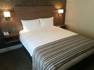 a large bed in a hotel room with two lamps at Corr's Corner Hotel in Newtownabbey