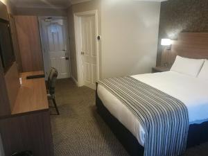 a hotel room with a bed and a desk and a door at Corr's Corner Hotel in Newtownabbey