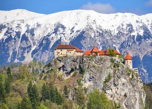 a building on top of a mountain with snow covered mountains at Apartment TiSa, Bled in Bled