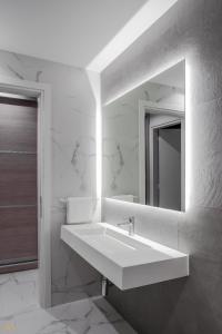 a white bathroom with a sink and a mirror at Elysium Boutique Apartments in Athens