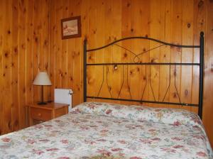 1 dormitorio con 1 cama y pared de madera en Bungalows Costa San Juan, en Soto de la Marina
