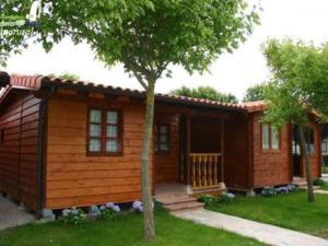 a small log cabin with a porch and a tree at Bungalows Costa San Juan in Soto de la Marina