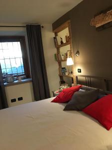 a bedroom with a bed with red pillows and a window at Maison Grivon Incanto e Vista sulla Valle in Charvensod
