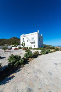 a white house on a sandy beach with a building at Thomas Villas on the beach Katapola in Katapola