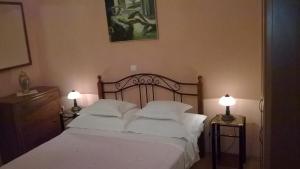 a bedroom with a bed with white sheets and two lamps at Apartments Mia in Podgora