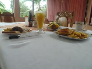 una mesa con dos platos de comida y un vaso de zumo de naranja en Posada Rural Río Celeste, en Rio Celeste