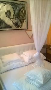ein Bett mit zwei weißen Kissen und einem Vorhang in der Unterkunft Apartments Mia in Podgora