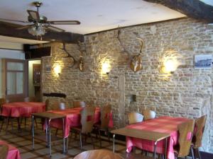a restaurant with red tables and chairs and a brick wall at HOTEL DE LA POMME D'OR in Bar-sur-Aube