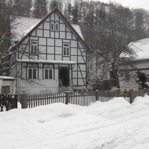 Ein weißes und schwarzes Haus mit einem Zaun im Schnee in der Unterkunft Waldhaus in Wernigerode