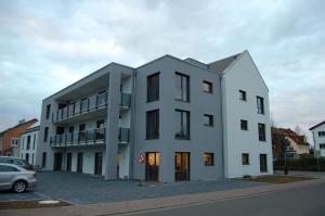 a white building with a car parked in a parking lot at Boardinghouse-Niedernberg in Niedernberg